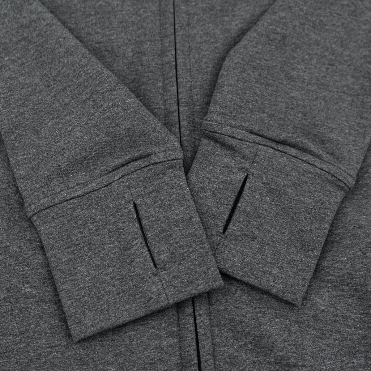 Close-up of a dark heather gray zip-up hoodie showing the sleeve cuffs with slanted openings and the center zipper.