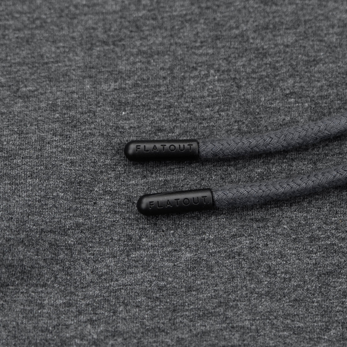 Close-up of dark gray heather fabric with black braided drawstrings and black FLATOUT end caps.