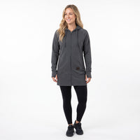 A woman modeling a dark gray zip-up hooded sweatshirt with black leggings and black sneakers, standing against a plain white studio background.