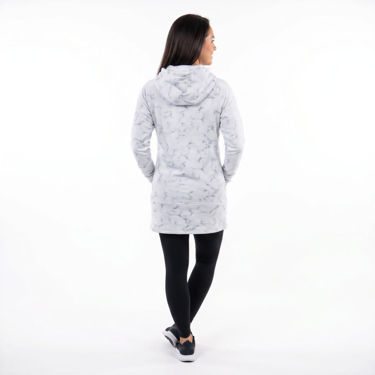 A woman is shown from behind wearing a light gray hooded jacket with a darker gray abstract pattern, paired with black leggings and black sneakers, against a solid white background.