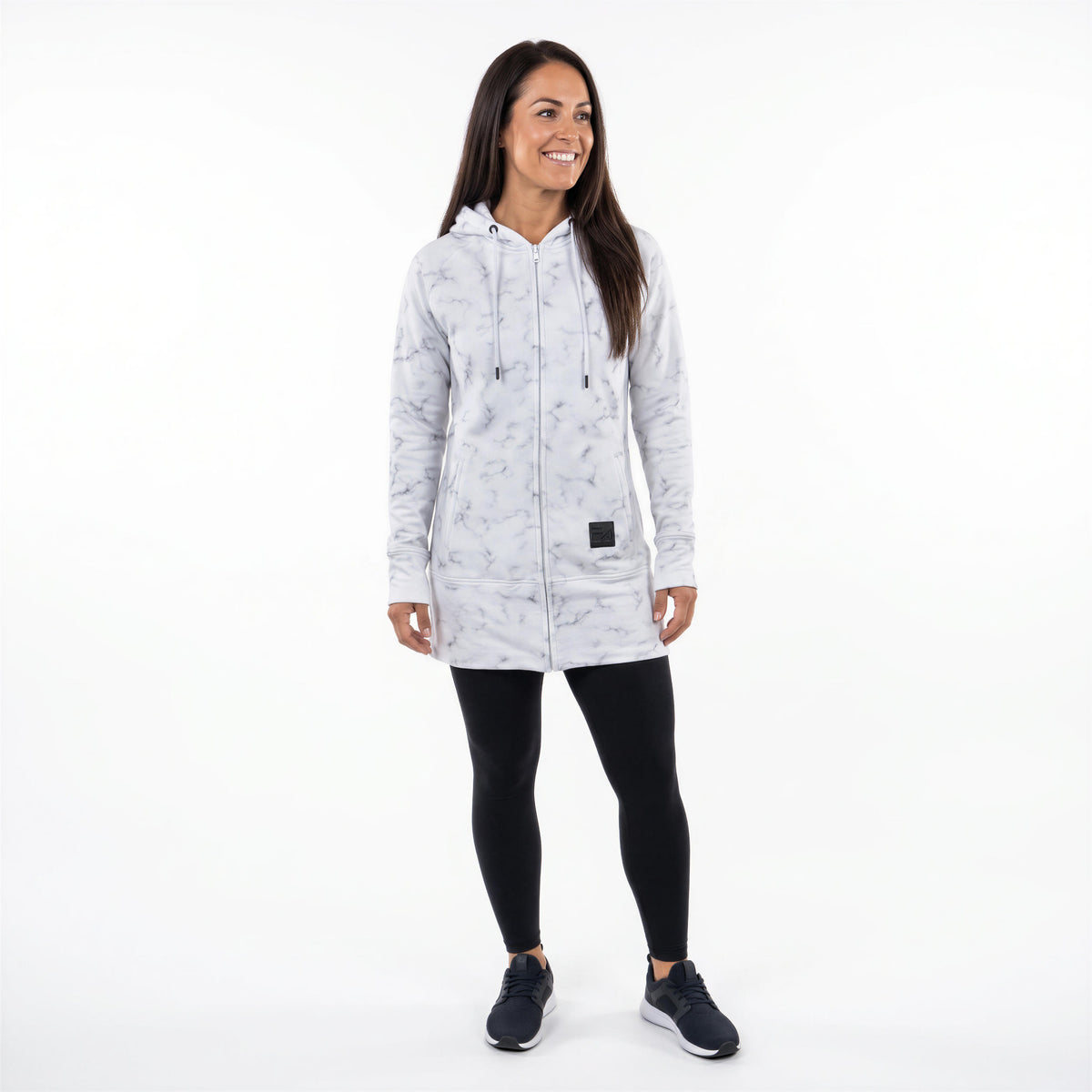 A woman modeling a light gray and white marble-patterned zip-up hooded jacket, paired with black leggings and dark sneakers, against a solid white background.