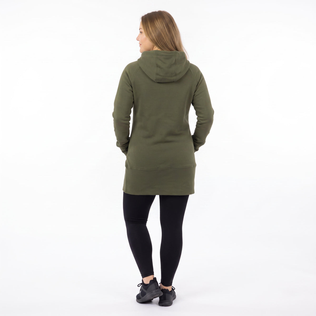A woman viewed from the back wearing an olive green hooded sweatshirt, black leggings, and black sneakers against a plain white studio background.