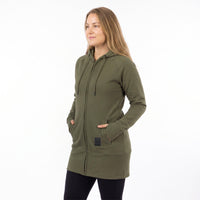 A woman wearing an olive green full-zip hooded sweatshirt with drawstrings and front pockets, standing against a plain white studio background.